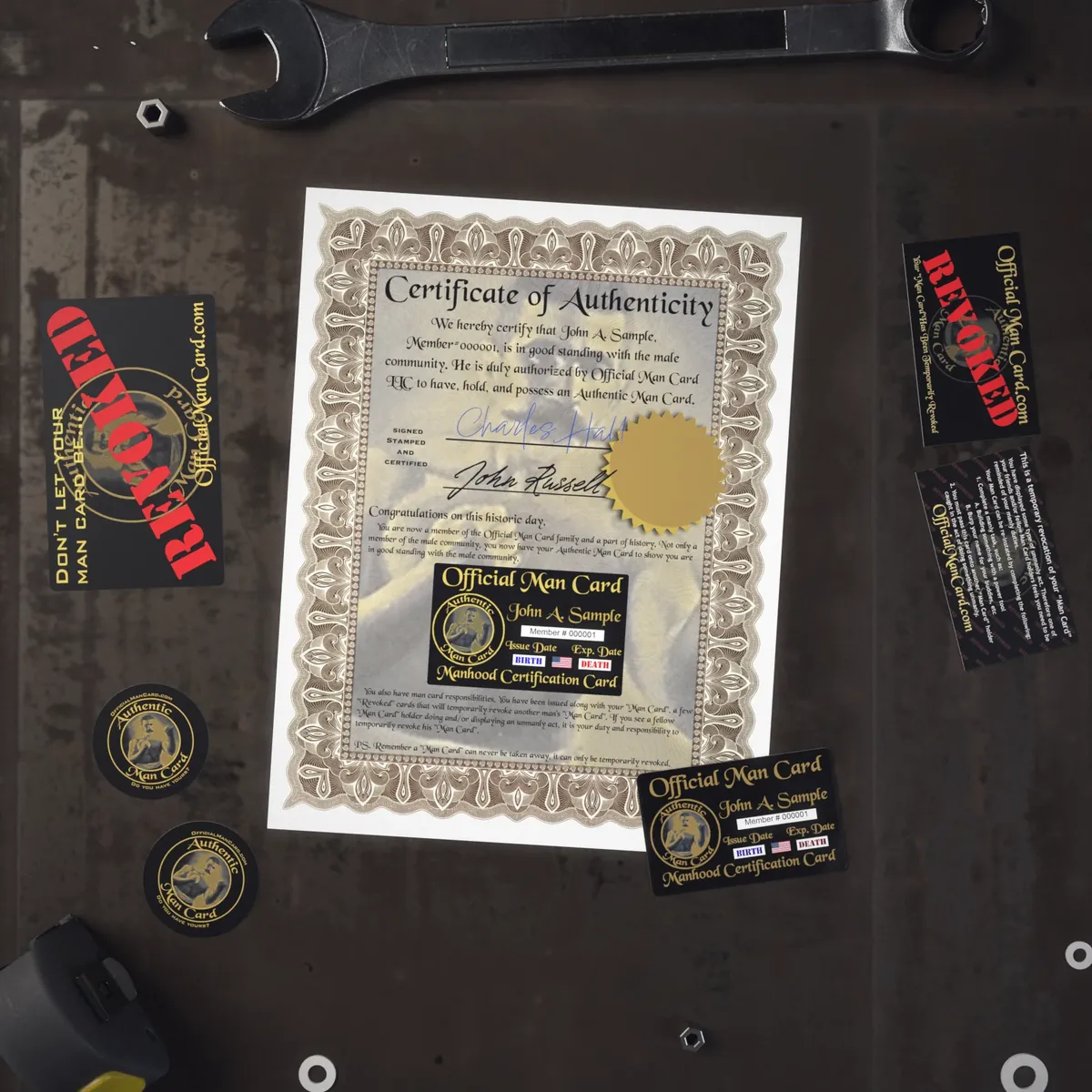 Everything in the Authentic Man Card package laid out on a workbench: the card, a certificate of authenticity, 2 Revoke Cards and 3 stickers